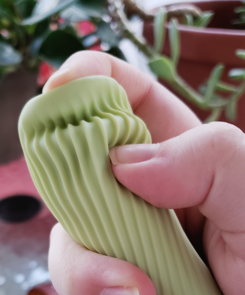 A person gripping the tip of the Zen, temporarily rumpling its silicone between their fingers.
