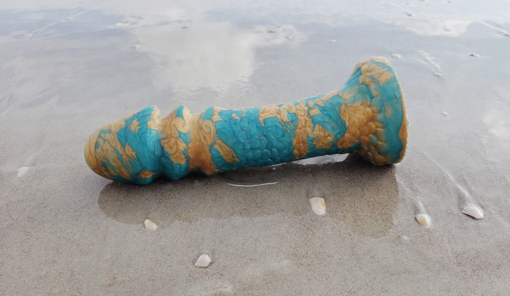 The Aqua-King laying among a few abandoned shells. The clouds are reflected on the wet sand.