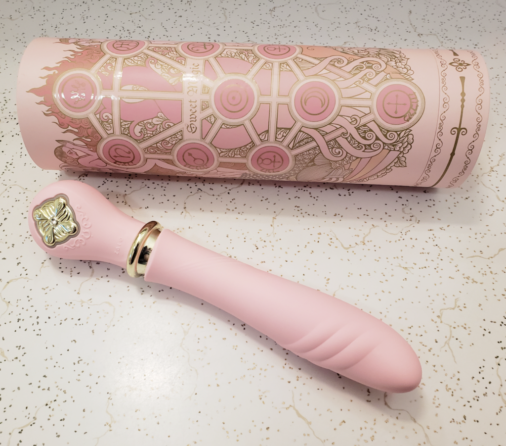 The Desire laying on a counter beside its tube-shaped box. The box features a symbol-heavy design that's very Tarot meets Sailor Moon.
