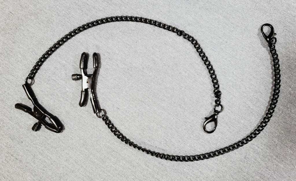 A pair of nipple clamps with long, thin chains attached to them. The chains have clip fasteners, similar to necklaces.