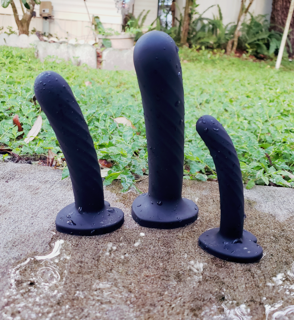 The Temptasia Twist dildos standing upright in a reflective puddle.
