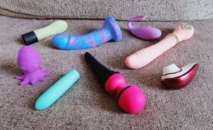 An assortment of sex toys laying on a couch.
