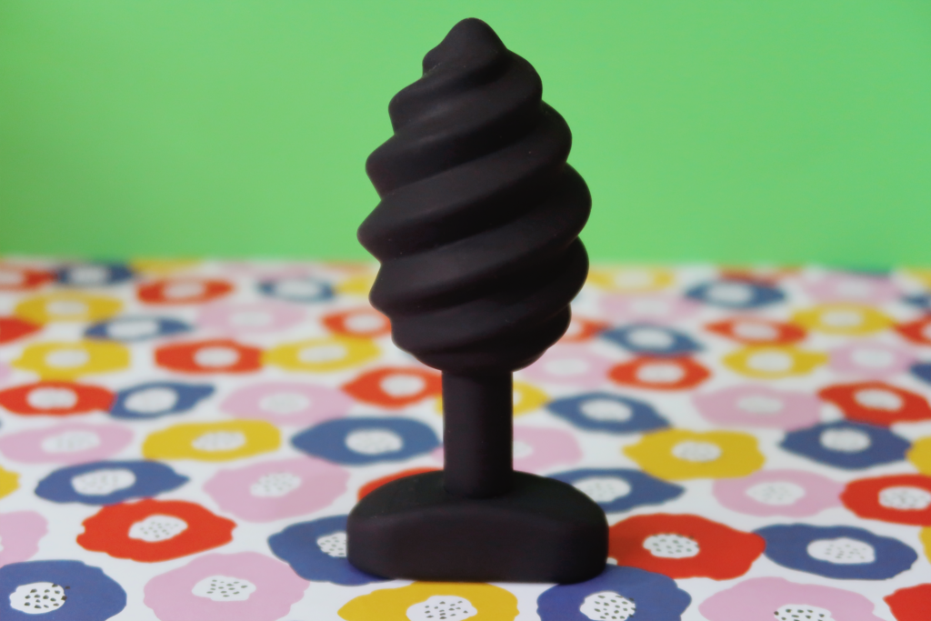 A black spiral-swirled butt plug standing upright.