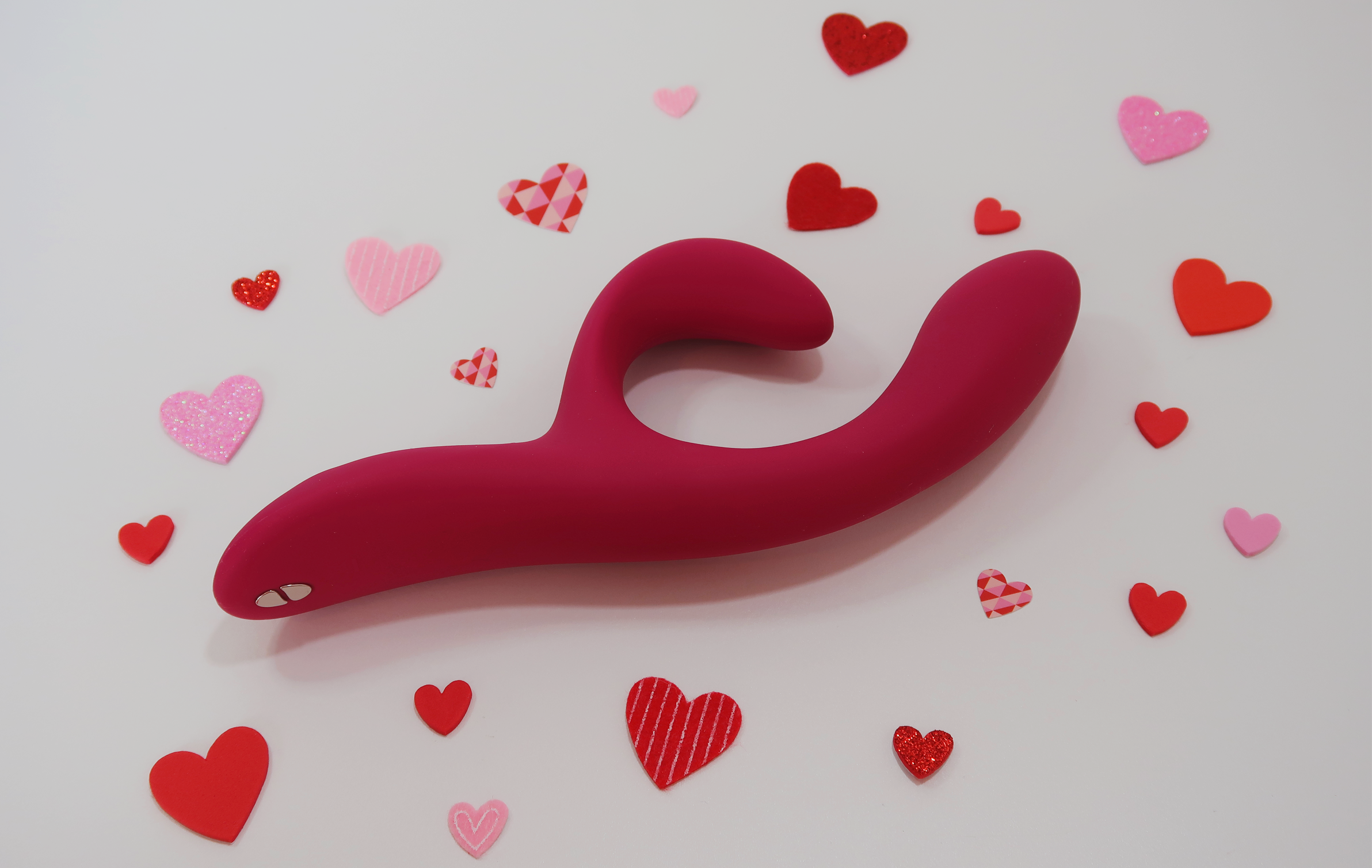 The Nova 2 dual stimulating vibrator laying on its side, surrounded by tiny craft hearts.