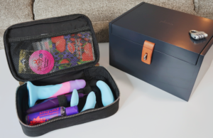 An open sex toy storage bag next to a closed, lockable sex toy storage box.