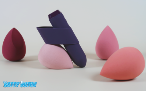 The Je Joue bullet propped up against a beauty blender to show off its profile. It has an extra ring of silicone on it that you can slip over your finger.